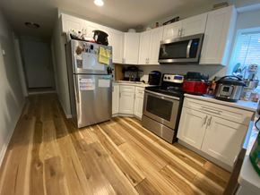 Chicago apartment for rent - A kitchen with wooden floors and white cabinets.