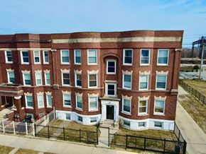 Chicago apartment for rent - A red brick building with a black fence in front.