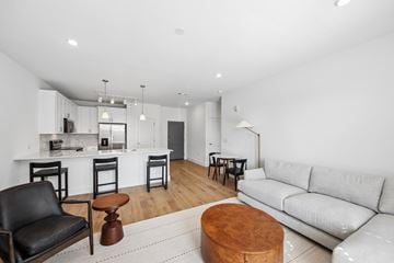 Naperville apartment for rent - A modern living room with a white couch and a kitchen area in the background.