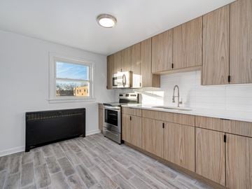 Chicago apartment for rent - A kitchen with wooden cabinets and a black radiator.