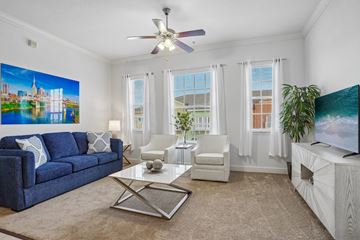 Clermont apartment for rent - A living room with a blue couch, a white chair, a coffee table, and a painting on the wall.