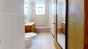 Skokie apartment for rent - A white tiled bathroom with a toilet, sink, and bathtub.