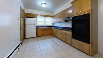 Skokie apartment for rent - A kitchen with a black microwave above the stove and a white refrigerator.