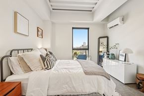 Chicago apartment for rent - A bedroom with a large bed and a window overlooking a cityscape.