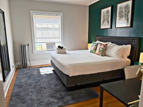 Evanston apartment for rent - A bedroom with a large bed and a window with blinds.