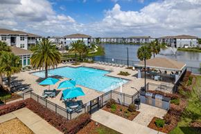 Kissimmee apartment for rent - A pool surrounded by a black fence with blue umbrellas.