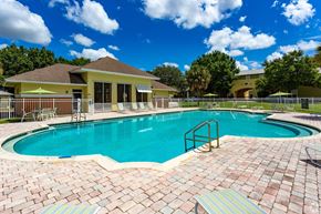 Clermont apartment for rent - A swimming pool surrounded by a brick patio and a yellow building in the background.