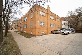 Chicago apartment for rent - A brick building with a parking lot in front.