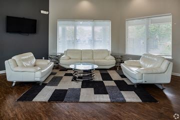 Orange Park apartment for rent - A living room with white leather furniture and a black and white rug.
