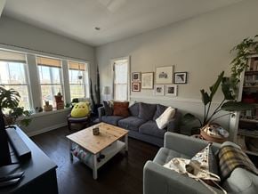 Chicago apartment for rent - A living room with a grey couch, a wooden coffee table, and a large window.