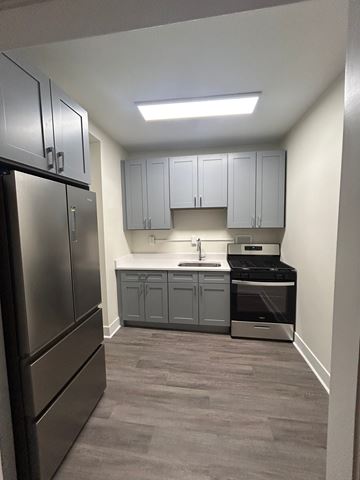 Evanston apartment for rent - A kitchen with a stainless steel refrigerator and grey cabinets.
