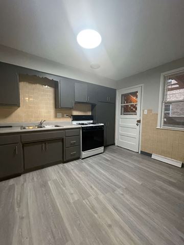 Chicago apartment for rent - A kitchen with a white door and a stove top oven.
