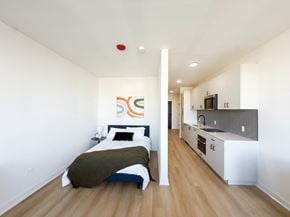 Chicago apartment for rent - A bedroom with a bed and a kitchen area in the background.