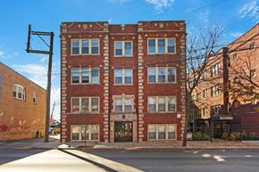 Chicago apartment for rent - A red brick building with a black awning on the corner of a street.