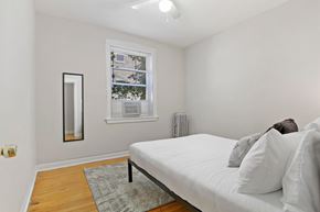 Chicago apartment for rent - A bedroom with a white bed and a window with blinds.