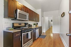 Chicago apartment for rent - A kitchen with dark wood cabinets and a black stove top oven.