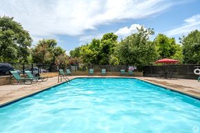 Lafayette apartment for rent - A large blue swimming pool surrounded by trees and lounge chairs.
