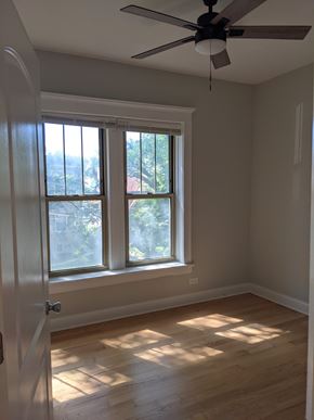 Chicago apartment for rent - A room with a ceiling fan and a window with sunlight coming through.