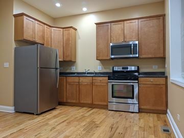 Chicago apartment for rent - A kitchen with wooden cabinets and a black stove top oven.