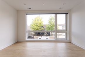 Chicago apartment for rent - A room with a large window overlooking a street with cars and trees.