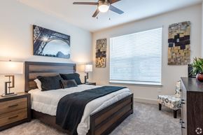 Clermont apartment for rent - A bedroom with a bed, two lamps, a ceiling fan, and a picture of the Eiffel Tower on the wall.