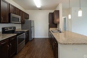 Orange Park apartment for rent - A kitchen with dark brown cabinets and a granite countertop.