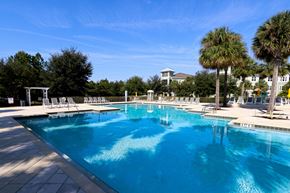 Clermont apartment for rent - A large swimming pool with a white fence and chairs around it.