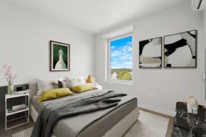 Chicago apartment for rent - A bedroom with a large bed and a window showing a blue sky.