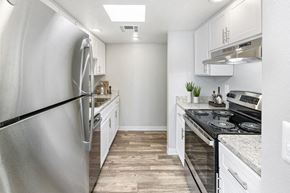 Tucson apartment for rent - Pet-Friendly Apartments in East Tucson, AZ - Lakeside Casitas - A Kitchen With White Cabinets, Stainless Steel Appliances, Recessed Lighting, And Wood Style Flooring.