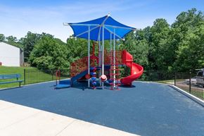 Dale City apartment for rent - Woodbridge, VA, Apartments Near Potomac Mills Mall - Brightwood Forest - A Playground With Red Slides, Climbing Structures, And A Blue Shade Canopy On Rubber Surfacing.