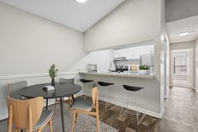 Orlando apartment for rent - Model Dining Room and Kitchen with Wood-Style Flooring and Hallway View at Rosehill Preserve Apartments located in Orlando, FL.