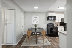 Tucson apartment for rent - Model Dining Room with Wood-Style Flooring and View of Kitchen with White Cabinets at Solano Springs Apartments located in Tucson, AZ.
