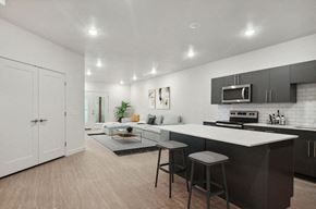 West Valley City apartment for rent - West Valley City, UT, Apartments with In-Unit Washer and Dryer - Sage Valley - A Kitchen With Large White Island, Dark Cabinets, Stainless Steel Appliances, And Sectional Sofa Seating Area.