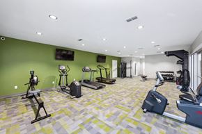 Jacksonville apartment for rent - a gym with weights and cardio equipment in a building with green walls