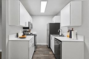 Sacramento apartment for rent - Model Kitchen with White Cabinets and Wood-Style Flooring at The Archer Apartments in Sacramento, CA.