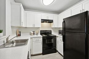 Sarasota apartment for rent - Model Kitchen with White Cabinets and Wood-Style Flooring at Huntington Place Apartments located in Sarasota, FL.