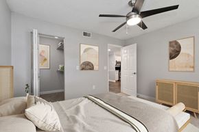 St. Petersburg apartment for rent - North St. Petersburg, FL, Apartments with In-Unit Washer and Dryer - Bridges at Bayside - A Bedroom With A Bed, Framed Art, A Ceiling Fan With Light, And A Spacious Closet.