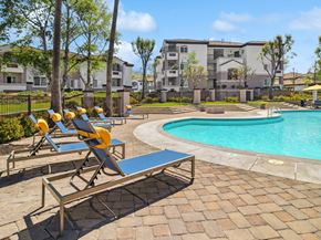 Moreno Valley apartment for rent - A poolside area with sun loungers and a bench.
