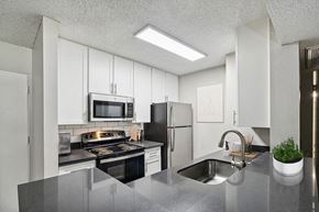 Anaheim apartment for rent - Model Kitchen with White Cabinets and Wood-Style Flooring at Madison Park Apartments located in Anaheim, CA.