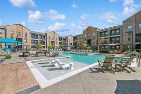 Aubrey apartment for rent - Aubrey, TX Luxury Studio Apartments - Aubrey Junction Apartments - Resort Style Swimming Pool With In Water Loungers, Sun Deck Seating, And View Of Apartment Buildings