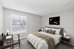 Albuquerque apartment for rent - Northeast Albuquerque, NM, Apartments with In-Unit Washer and Dryer - Indigo Park - Cozy Bedroom With Upholstered Bed, Neutral Bedding, Desk Workspace, And Wide Window With White Blinds.