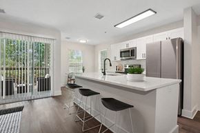 Charlotte apartment for rent - Model Kitchen with White Cabinets, Wood-Style Flooring and Patio Accessibility at Park at Caterina Apartments located in Charlotte, NC.