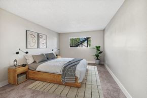 Mesa apartment for rent - Mesa, AZ, Apartments Near Light Rail - The District at Fiesta Park - Cozy Bedroom With Wood Platform Bed, Neutral Carpet, Modern Wall Art, Nightstands, And Window Overlooking Courtyard.