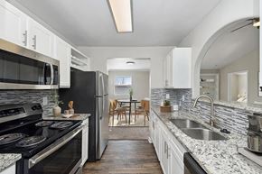 Lewisville apartment for rent - Model Kitchen with White Cabinets and Wood-Style Flooring at Hidden Creek Apartments in Lewisville, TX.