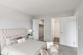Dale City apartment for rent - 2-Bedroom Apartments in Woodbridge, VA - Brightwood Forest - A Bedroom With A Tufted Headboard Bed, Neutral Decor, And Carpeted Floors.