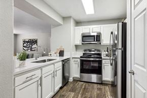 Las Vegas apartment for rent - Apartments Near Walmart - Monterra - Modern Kitchen With White Cabinets, Quartz Look Counters, Stainless Steel Refrigerator, Microwave, And Gas Range