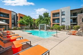 Surprise apartment for rent - Surprise, AZ, Apartments with In-Unit Washer and Dryer - Harmony at Surprise - A Swimming Pool With Clear Blue Water, Orange Lounge Chairs, And View of Modern Apartment Buildings.