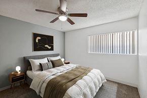 Tucson apartment for rent - 3-Bedroom Apartments in East Tucson, AZ - Lakeside Casitas - A Bedroom With A Neatly Made Bed, Bedside Tables, Ceiling Fan, Framed Wall Art, And A Window.