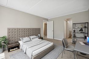 Burnsville apartment for rent - One-Bedroom Affordable Apartments in Burnsville, MN - Elevate on Parkway - A Bedroom With a Tufted Headboard, Neutral Carpet, Matching Nightstands, And Desk Workspace.