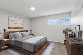 Kansas City apartment for rent - Pet-Friendly Apartments in Kansas City, MO - Parc at Creekside Apartments - Spacious Bedroom With Wood Platform Bed, Nightstands, Lamps, Soft Carpet, Wall Art, Ceiling Light, and Windows.